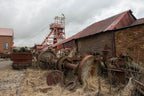 Abandoned mining equipment and buildings under a cloudy sky