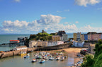 Harbor scene with boats and colorful buildings under a blue sky.
